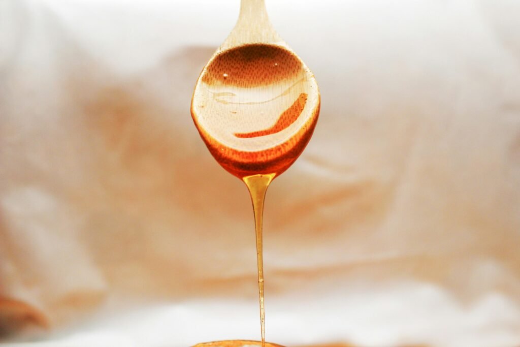 Honey drips from a wooden spoon in a warm and inviting still life setup.
