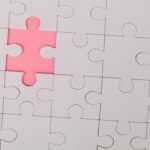 Close-up of an unfinished puzzle with a pink missing piece, highlighting emptiness.