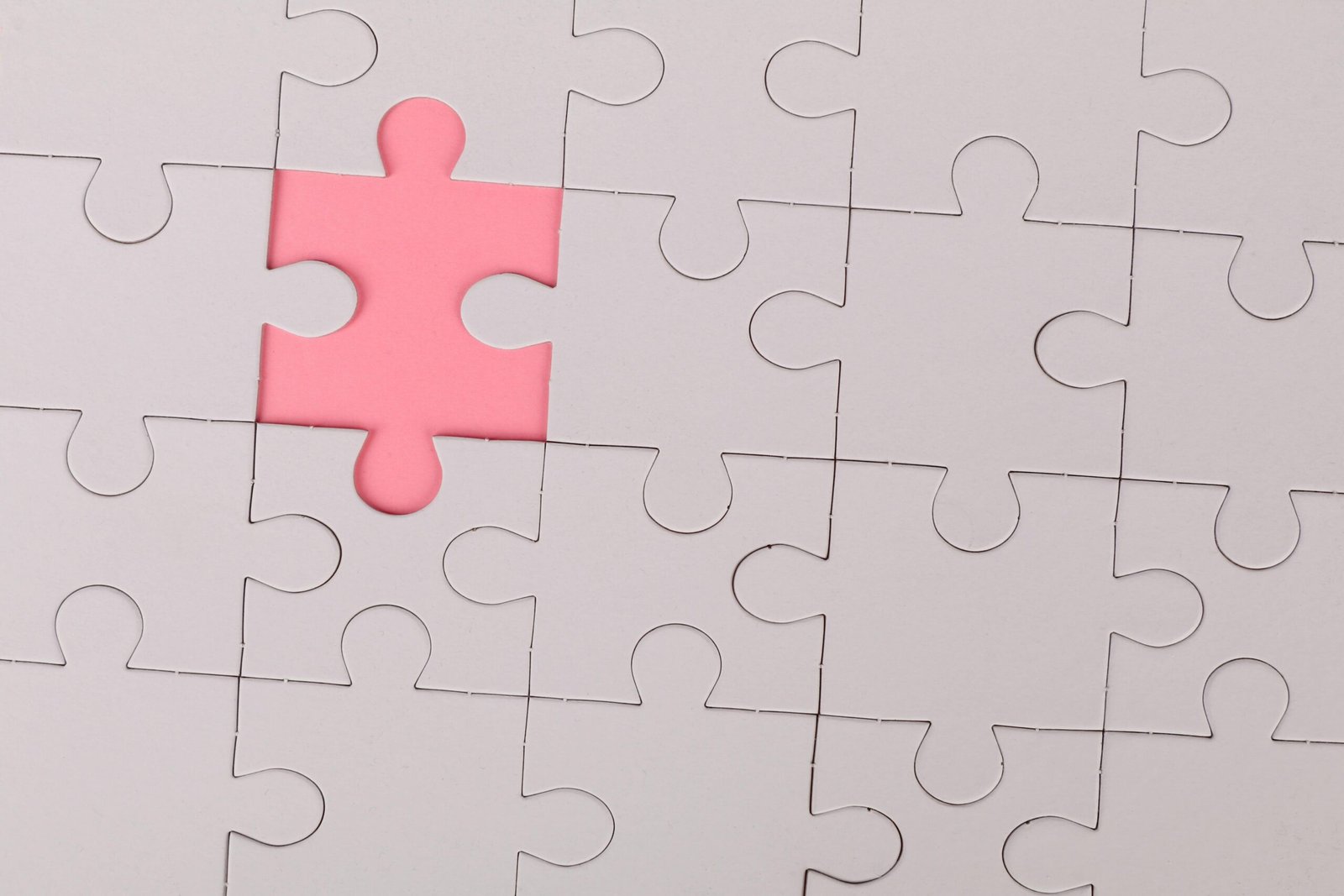 Close-up of an unfinished puzzle with a pink missing piece, highlighting emptiness.