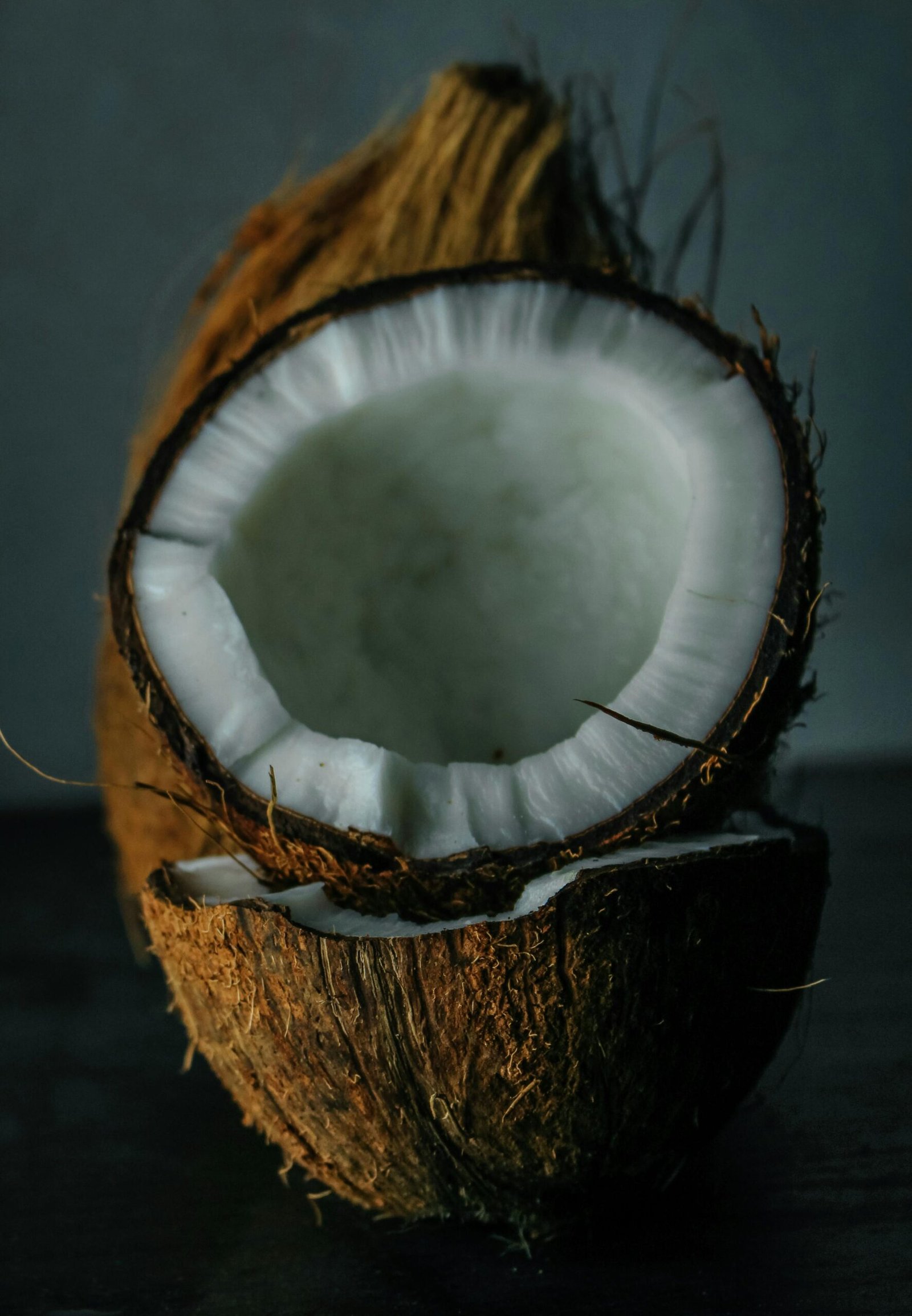 A detailed view of a freshly cracked coconut showcasing the white flesh and fibrous shell.
