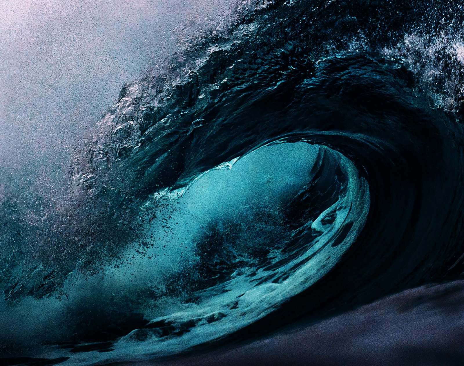 Dramatic capture of a powerful ocean wave with dark blue tones.